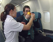 Air NZ crew member demonstrates mask to blind passenger