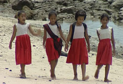 Primary school girls walk on beach in Samoa
